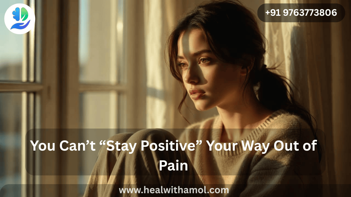 Person sitting by a window in soft light reflecting on emotional pain and healing from toxic positivity.